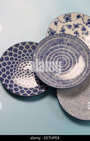 Set of blue ceramic plates and bowls on a light background. Ceramic tableware close up. Stock Photo