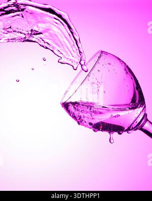 Liquid splashes from tilted glass with purple lighting. Stock Photo