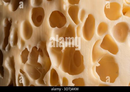 Close-up of swiss cheese with large irregular holes and creamy yellow texture, macro food detail Stock Photo