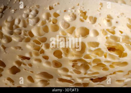 Close-up of swiss cheese with irregular holes and creamy yellow texture Stock Photo