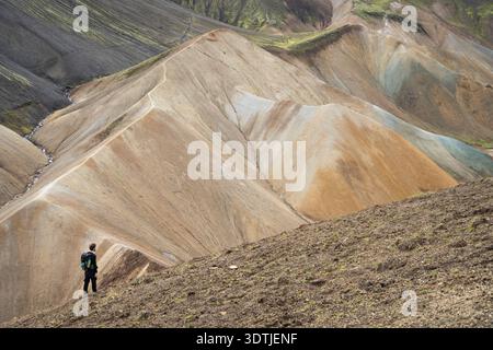 Hiker on a ridge looking on colorful mountains and ridges in front of him, Highlands, Iceland Stock Photo