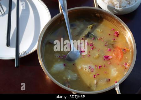 A plate of soup with a spoon, an empty plate with chopsticks and a fork. Stock Photo