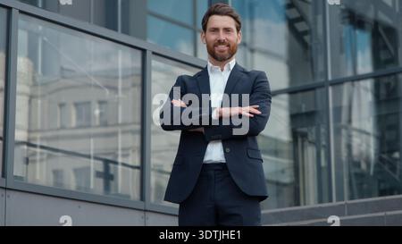 Successful smiling mature Caucasian business man businessman crossing hands posing in city smile carefree male entrepreneur leader executive Stock Photo