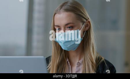 Portrait Caucasian business woman typing laptop wearing face medical mask businesswoman in office female entrepreneur girl marketing manager using Stock Photo