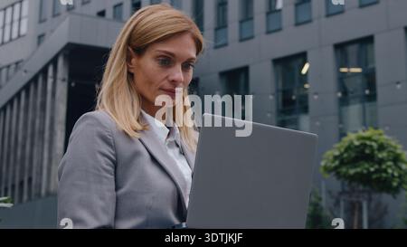 Thoughtful serious Caucasian middle-aged business woman typing laptop in city pensive businesswoman female working busy with computer technology Stock Photo