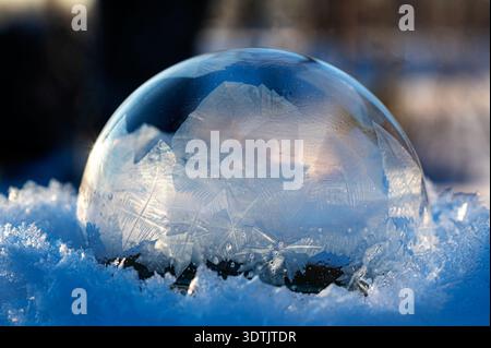 picture with frozen bubble in the snow, beautiful frosty patterns on a frozen soap bubble, winter, frosty background, frozen bubble, soap bubble on sn Stock Photo