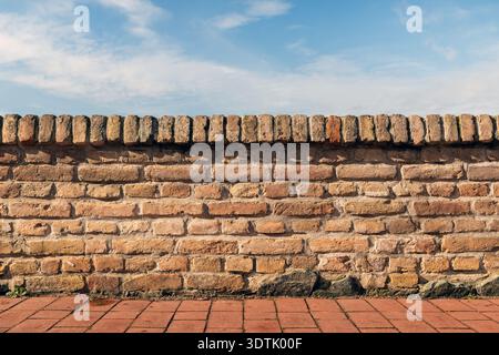 Old brick wall with terracotta coping and blue sky background, selective focus Stock Photo