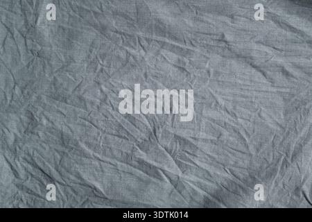 Close-up texture of heavily crumpled gray fabric with deep creases, fine weave, and soft shadows creating tactile depth and abstract textile detail. T Stock Photo