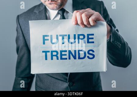 Businessman holding paper with Future trend text printed, symbolizing forecasting, innovation, market direction, and strategic business planning. Sele Stock Photo