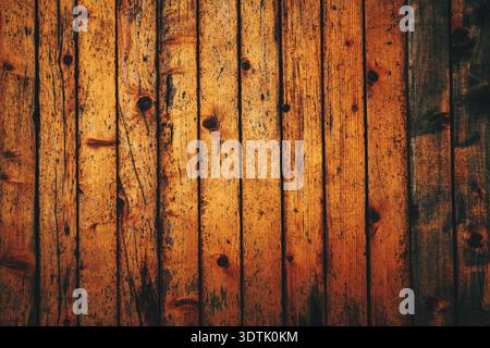 Weathered vertical wooden plank wall texture in warm orange tones, showing aged grain, cracks, and rustic surface detail, distressed texture backgroun Stock Photo