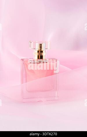 A luxurious perfume bottle sits gracefully on soft pink organza fabric. The elegant design and soothing background create a serene atmosphere, highlig Stock Photo