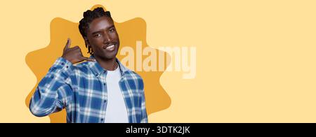 Young Man Showing Call Gesture With Cheerful Smile in Colorful Setting During Daytime Stock Photo
