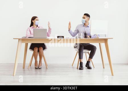 Meeting Between Two Workers at a Desk With Laptops and Masks During Business Hours Stock Photo