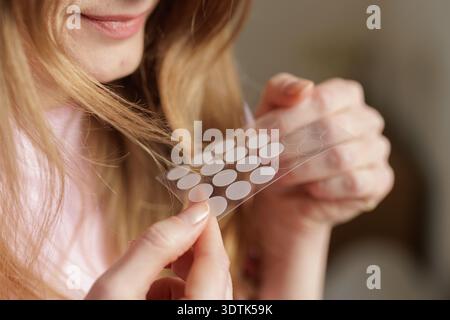 Closeup of woman holding hydrocolloid acne patches for blemish treatment. Concept of dermatology skincare routine and cosmetic product advertising use Stock Photo