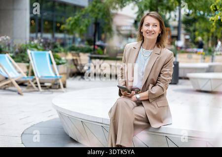 Portrait of young adult mid age businesswoman in formal dress suit outdoors. Happy confident stylish elegant business woman female person. Financial Stock Photo