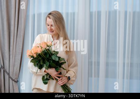 Female portrait with fresh flowers in cozy interior. Suitable for lifestyle branding, greeting campaigns and romantic themes. Stock Photo