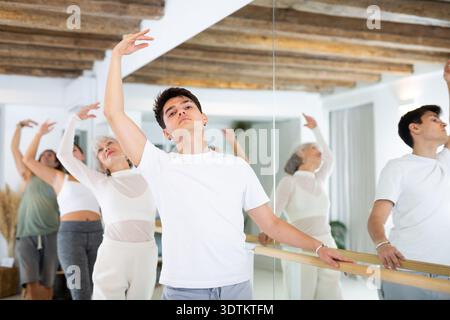 Diligent young man doing choreography at ballet barre Stock Photo