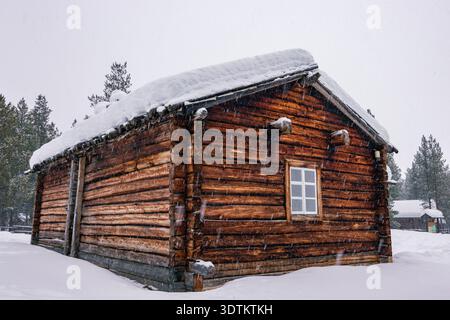 Traditional red wooden cabin covered in deep snow in the forest of Inari, Finnish Lapland. Stock Photo