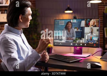 Diverse colleagues connect virtually on video call to collaborate, share ideas and discuss ongoing business projects. Asian businessman remotely handling professional online meeting with shareholders. Stock Photo