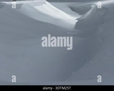 Deep snowdrift and carved snow field with soft light creating an abstract winter landscape of textures Stock Photo