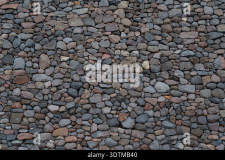 Rock wall made of small rocks on concerete background.  Background image, texture. Stock Photo