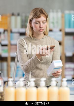 Girl in autumn clothes scans code on cough syrup to check expiration date Stock Photo