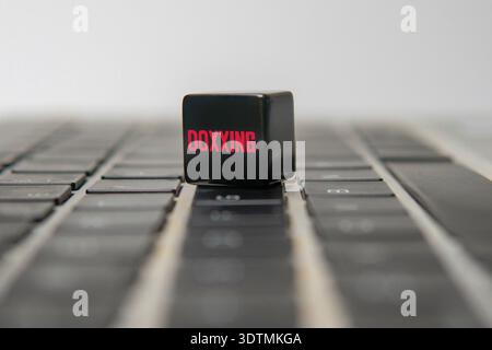 Black cube with red DOXXING text on a black laptop keyboard. Cyberbullying, identity theft, online harassment, and data privacy risks concept. Stock Photo