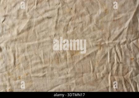 dirty light brown cloth texture background, stained fabric with visible woven thread pattern and irregular wrinkles, full frame closeup, grunge Stock Photo
