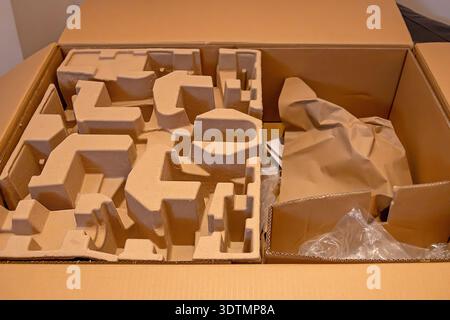 Open cardboard shipping box containing molded pulp packaging inserts and some brown paper filler Stock Photo