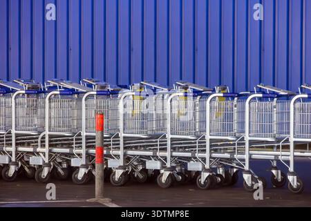 Rows of metal shopping carts trolleys are a common sight at supermarkets and retail stores Stock Photo