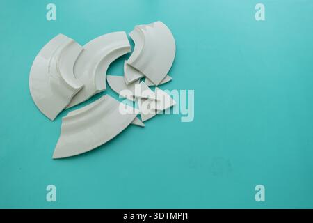 Broken white plates on light blue surface Stock Photo