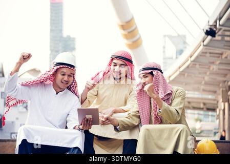 Arab team hold digital tablet uae union teamwork people. Digital marketing arab group of people using smart tablet discuss modern muslim UAE city. Ent Stock Photo