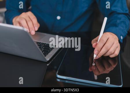 Man working remote with laptop and digital tablet. Student learning online, writing notes with stylus. Modern technology for business productivity and Stock Photo