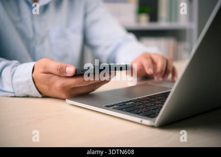 Businessman using mobile phone for online banking and two factor authentication on laptop. Security technology for payment and financial transaction. Stock Photo