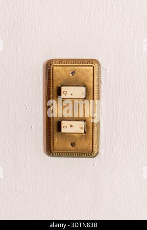Vintage brass light switch on textured white wall Stock Photo