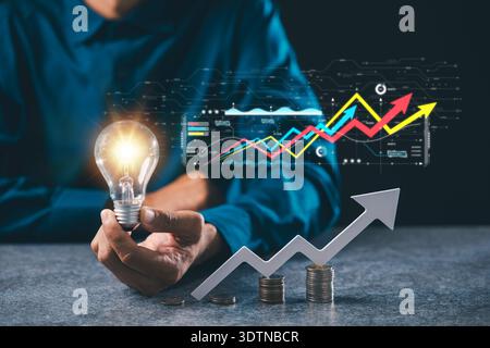 Business idea growth concept solution marketing shown within lightbulb, hand holds bulb with creative financial strategy using digital data charts and Stock Photo