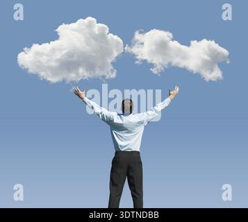 Beautiful clouds and happy young man with his hands up.Concept image on cloud computing and rest Stock Photo