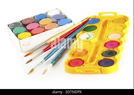 Set for painting. Palettes of watercolor paint and used brushes on white background. SDOF Stock Photo