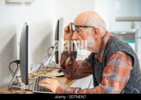Senior man working on computer at desk. Stock Photo