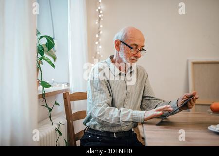 Elderly man using tablet, shopping online. Stock Photo