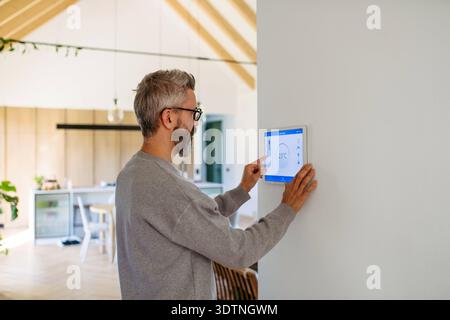 Man using smart home control panel. Man using smart home control panel, adjusting temperature. model released Stock Photo