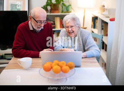 Loving elderly couple exploring digital world together, using laptop. Loving elderly couple exploring digital world together, using notebook. model re Stock Photo