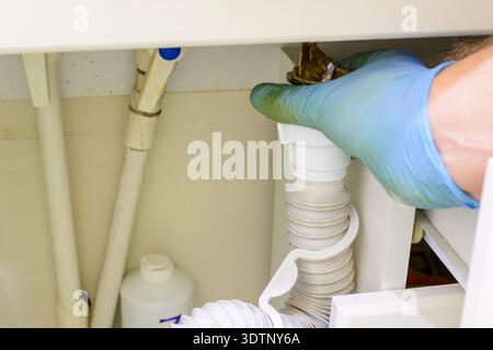 The drain pipe clogged with dirt and debris. Sewage cleaning. Plumbing services. Elimination of congestion in the drain pipe close-up. Stock Photo