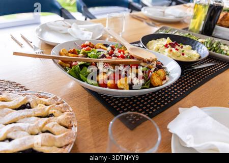 Dining table displaying oval salad bowl with two wooden spoons, lattice pie, mashed potatoes Stock Photo