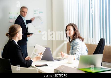 Focused professionals discussing reports. Serious business collaboration and strategic planning in a diverse team. Stock Photo