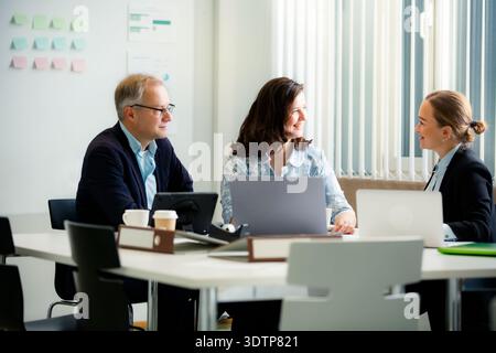 Confident female leader collaborating with diverse professional team in office. Real people working together. Empowered woman Stock Photo