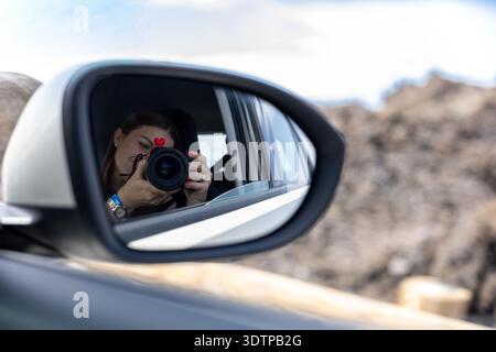 Female Photographer Shooting Camera Reflection In Car Mirror During Mountain Road Trip Travel Stock Photo