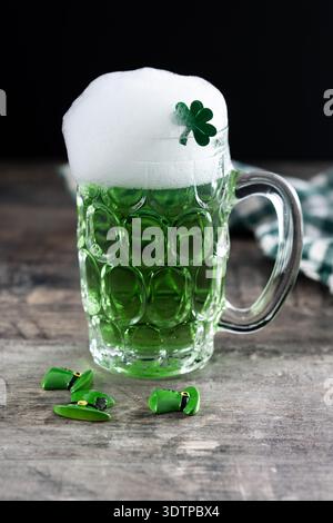 Pouring Green beer mug with foam for St. Patrick’s Day on black wooden table and black background Stock Photo