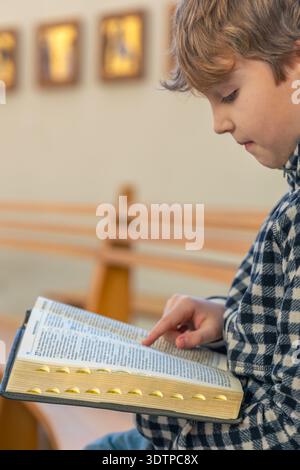 Focused boy reading Bible in church. Quiet prayer. Stock Photo