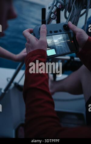 Man's hands holding drone controller on boat deck flying UAV whi Stock Photo